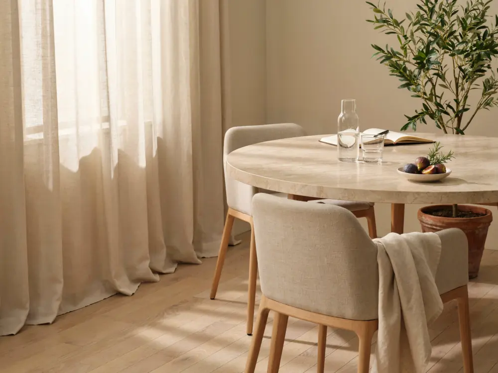 Sala de consulta luminosa con mesa redonda de piedra y un olivo
